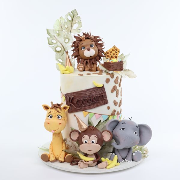 קארין עמנואל עם עוגה מעוצבת סופר גבוהה מקושטת בדפי אורז ועם חיות הספארי אריה ג׳ירפה קוף פיל מפוסלים בבצק סוכר