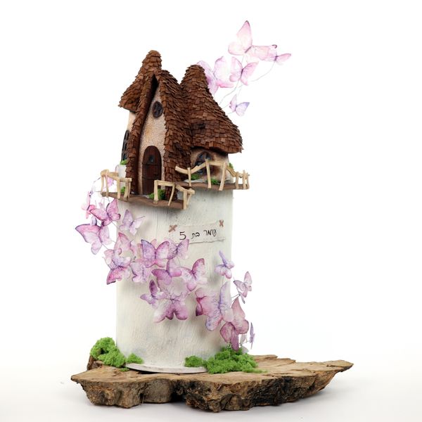 עוגה מעוצבת סופר גבוהה מצופה בטקסטורת שוקולד עם פסלים של טירה מפוסלים מבצק סוכר ופרפרים מנייר אורז