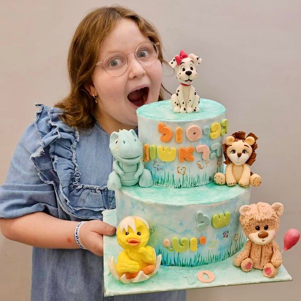 יוטי עם עוגת בצק סוכר הראשונה שלה עם הדמויות דובי אריה אפרוח דינוזאור כלב