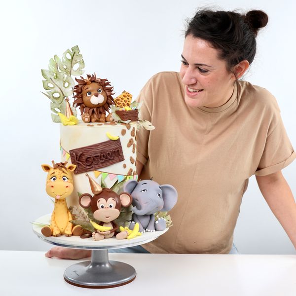 מגוון קורסים לעיצוב עוגות בבצק סוכר קארין עמנואל עם עוגה מעוצבת סופר גבוהה מקושטת בדפי אורז ועם חיות הספארי אריה ג׳ירפה קוף פיל מפוסלים בבצק סוכר