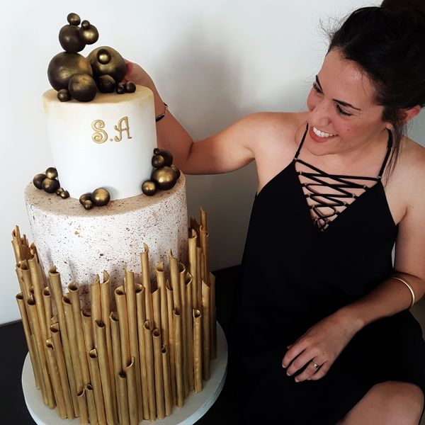 קארין עמנואל עם עוגת חתונה מעוצבת ב-3 קומות בזהב, לבן ושחור מפוסלת בבצק סוכר