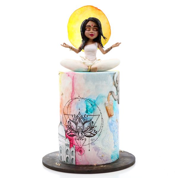 קארין עמנואל עם עוגה מצוירת ונערה הודית מפוסלת בבצק סוכר ושמש מאחוריה