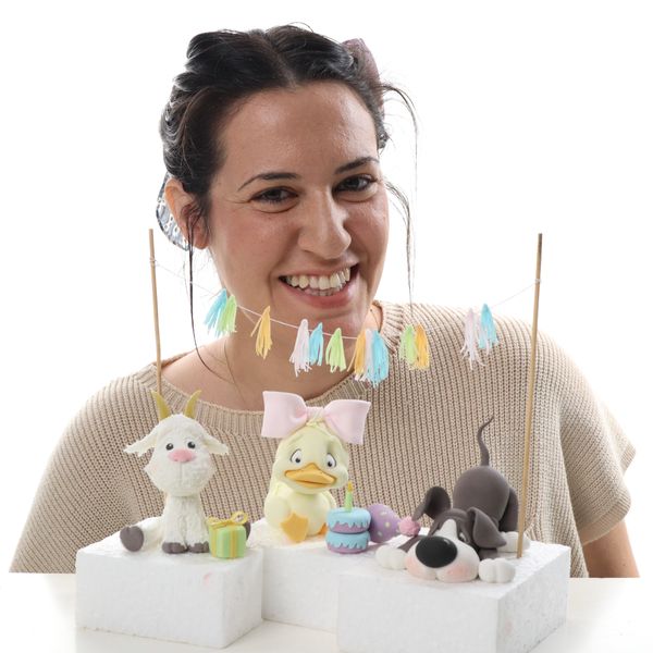 קארין עמנואל עם הדמויות כלב ברווזה עיזה מפוסלות בבצק סוכר